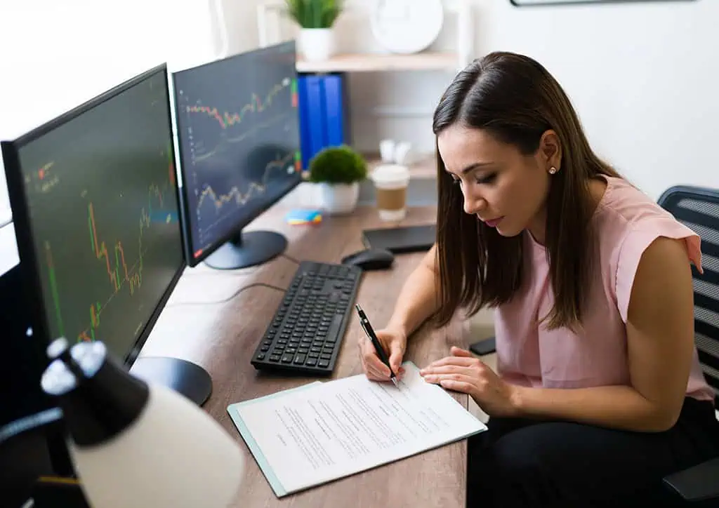 Passive vs Active Investing: Which Path Builds Wealth? 4 Trader reviewing a futures trading plan on dual monitors to build trading discipline